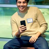 International Anchor Allies Winter 2026 First Mixer - a smiley male student poses for a picture whiles holding his phone